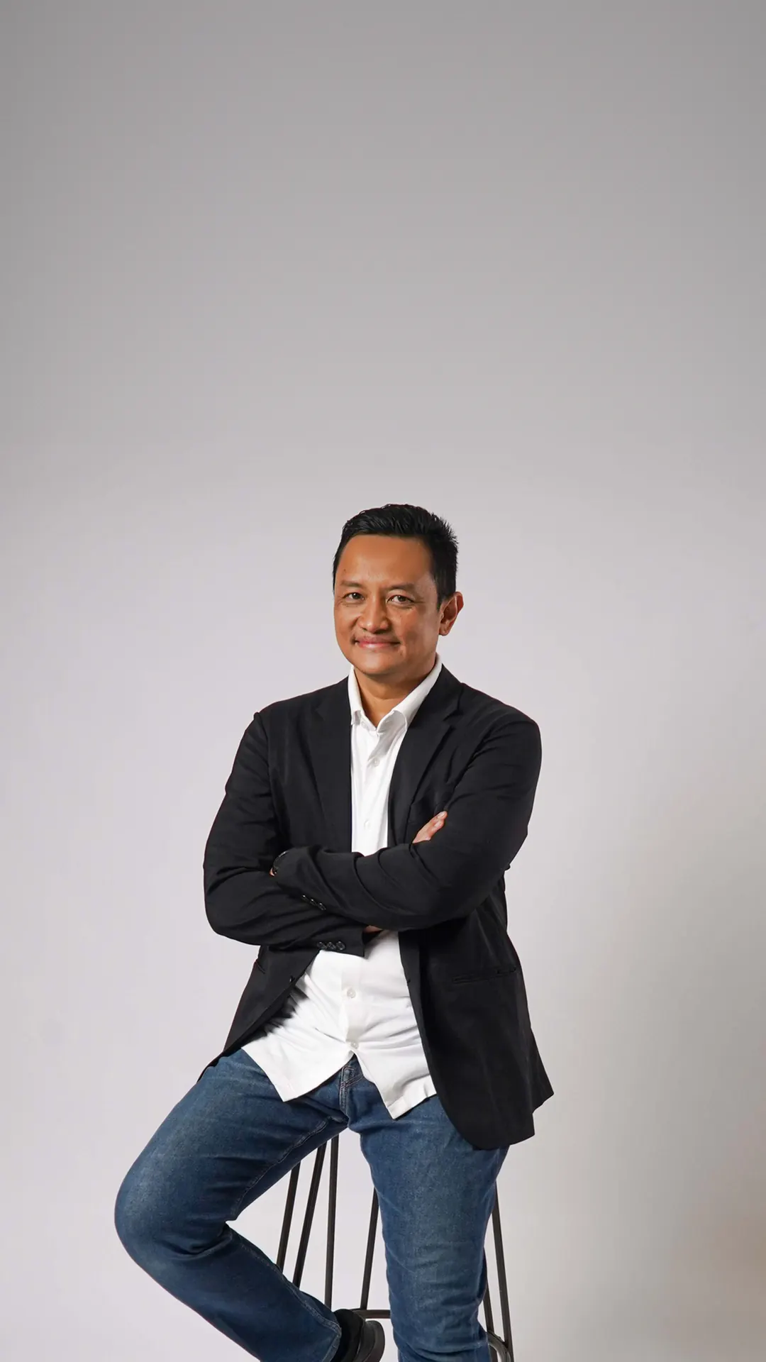 Herwin Muchtar berjas hitam, duduk di kursi tinggi
